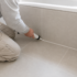 Handwerker erneuert Fugen im Badezimmer mit einer Kartuschenpistole.